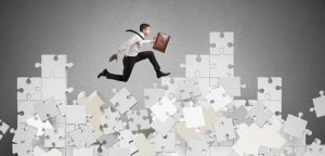 Businessman over a mountain by puzzle falling